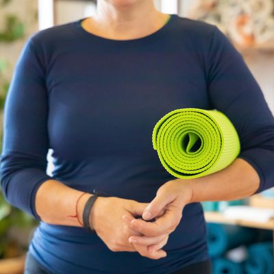 A yoga mat rolled up next to a small plant.