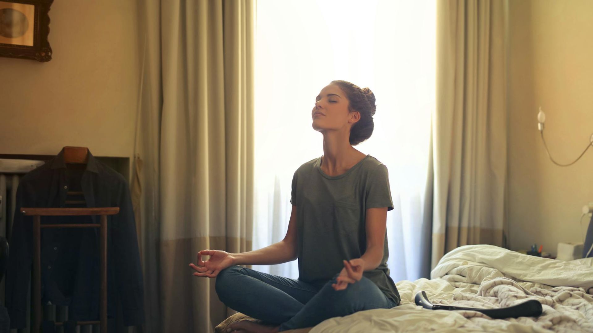 Serene woman in a meditative yoga pose in a dark room.
